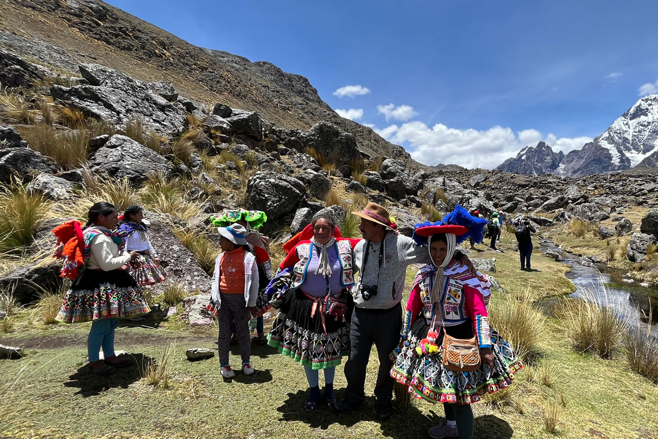 Menschen in traditioneller Kleidung vor Bergkulisse