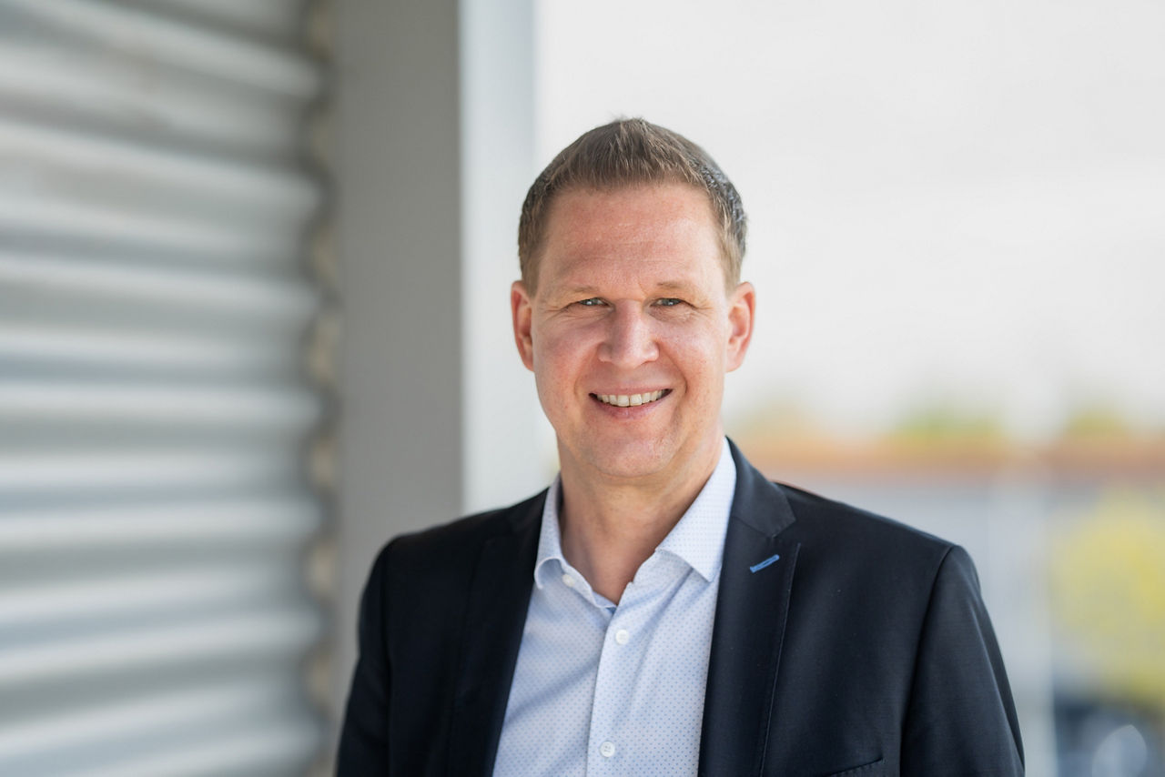 Mann mit Brille in der Hand schaut auf das Modell einer Immobilie