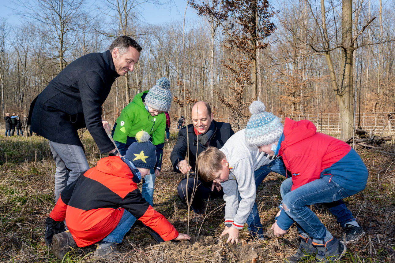 Zwei Männer und vier Kinder pflanzen einen Baum