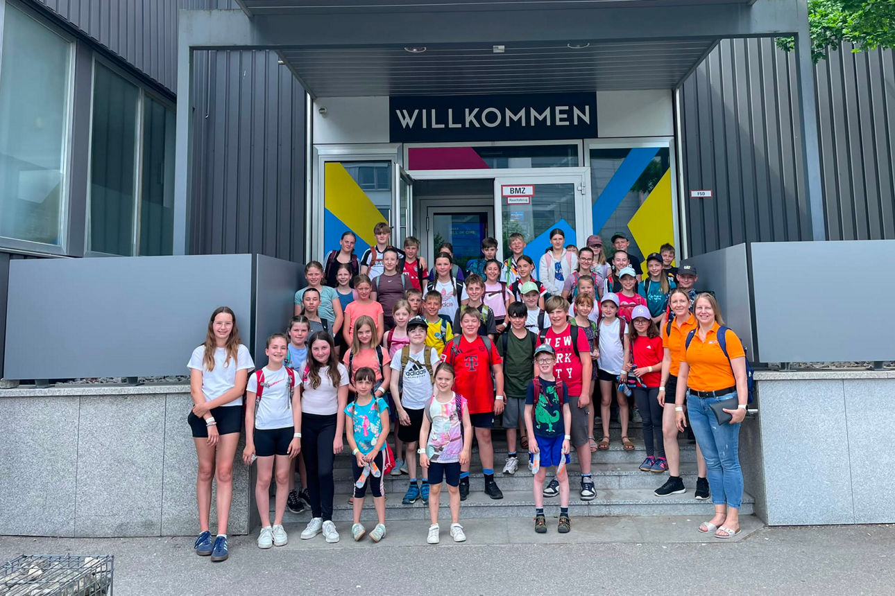 Die Kinder stehen zusammen mit den Betreuern der VR-Bank Isar-Vils vor der MAXX-Arena..