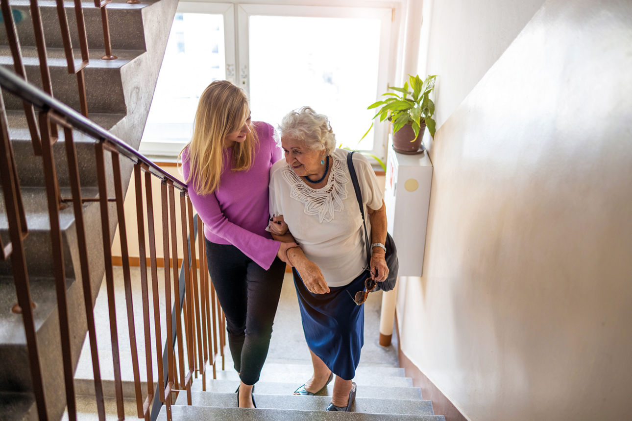 Frau hilft Seniorin die Treppe hoch