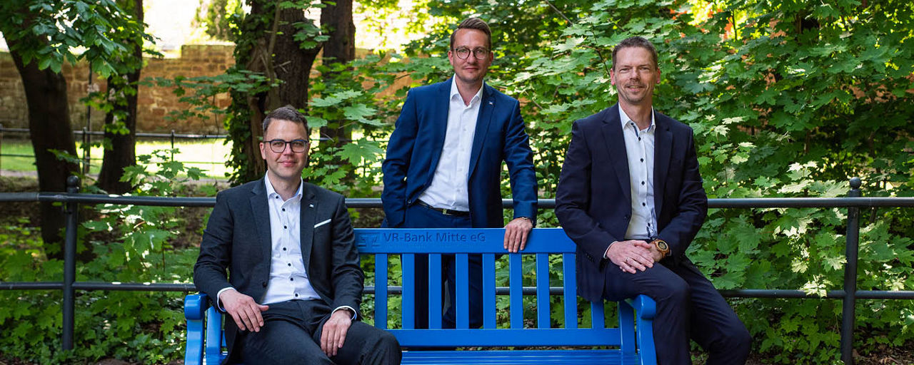 Drei Männer an einer blauen Bank