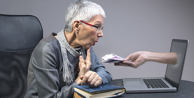 Eine Frau sitzt am PC und bekommt Geld gereicht