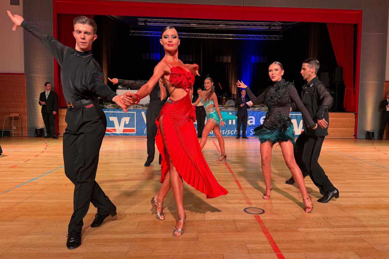 Mehrere Tanzpaare auf dem Parkett in glitzernden Kleidern