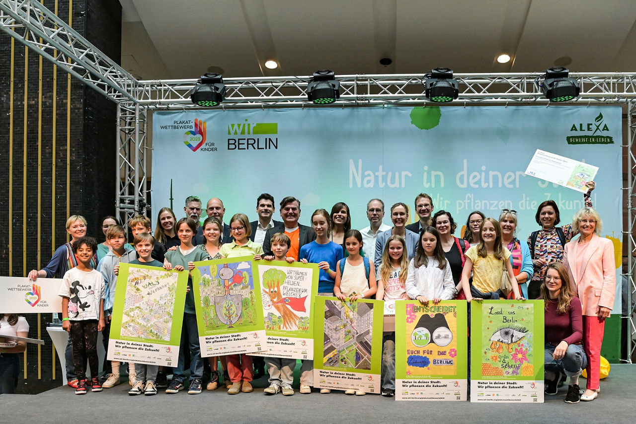 Aller Gewinner des Plakatwettbewerbes steht mit Jurymitgliedern vor ihren Plakatentwürfen