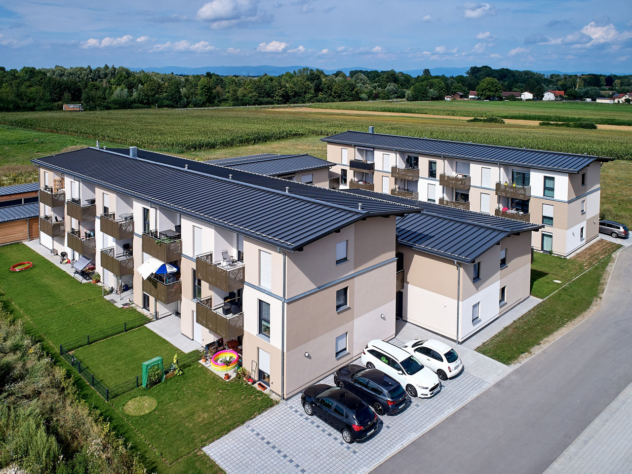 Mehrfamilienhaus mit blauem Himmel und Wiese im Hintergrund