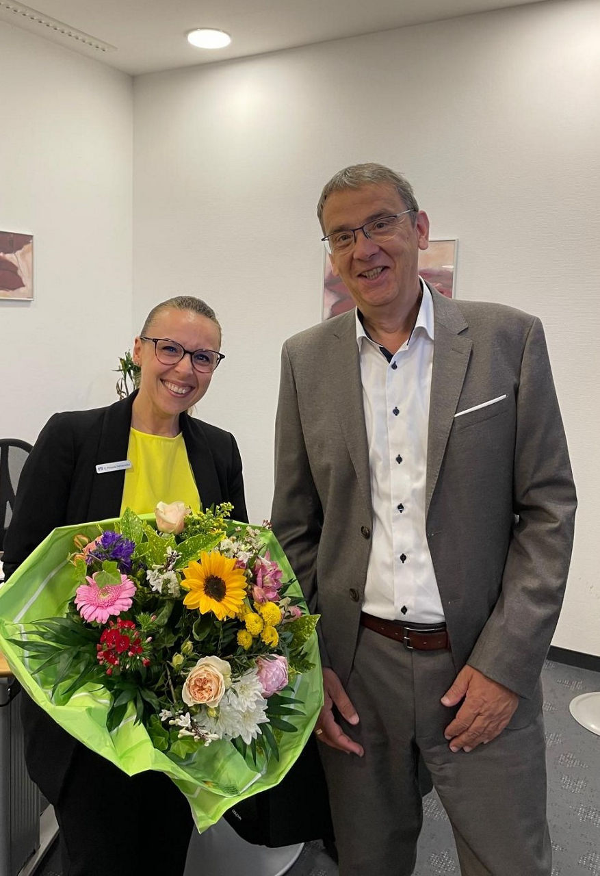 Voba Vorstand Herr Haas überreicht im Büro Frau Posada Fernandez einen Blumenstrauß