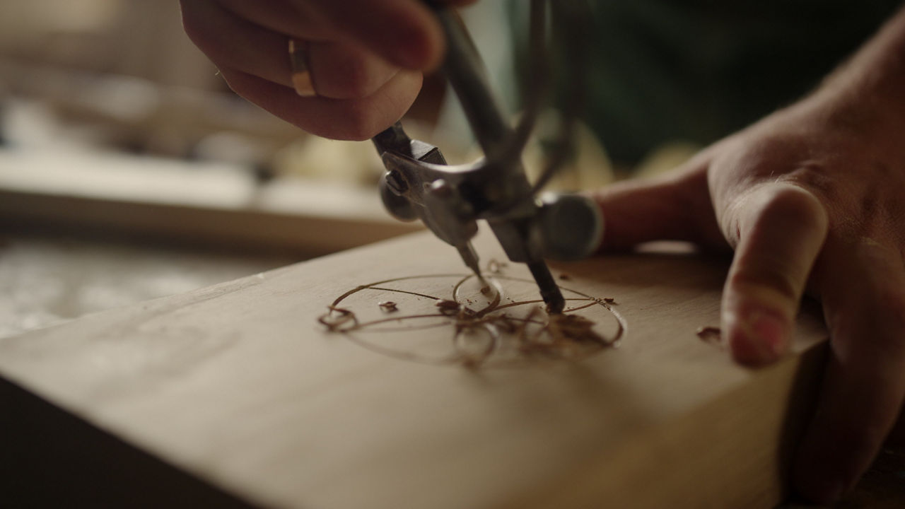 Mit einem speziellen Zirkel-Werkzeug wird ein Stück Holz per Hand graviert