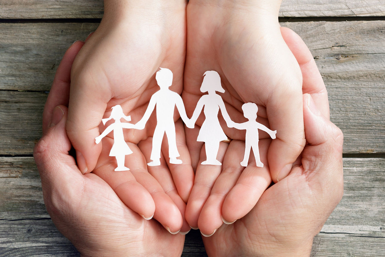 Hände halten einen Scherenschnitt als Familie