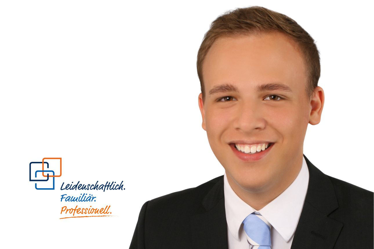 Marius Pröbstl, lächelnd, mit kurzen braunen Haaren und einer hellblauen Krawatte.