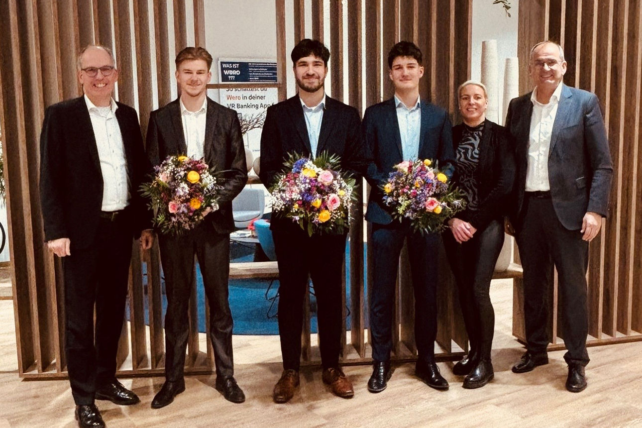 Sechs Personen bei Ehrung mit Blumensträußen in modernem Innenraum, Gruppenfoto