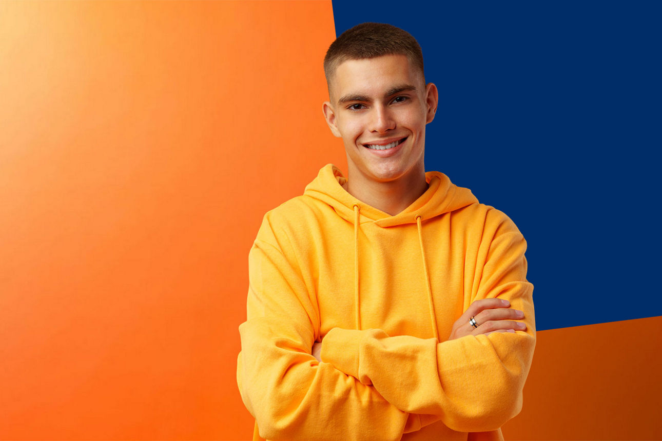 Jungendlicher im gelben Pullover vor orange-blauer Wand
