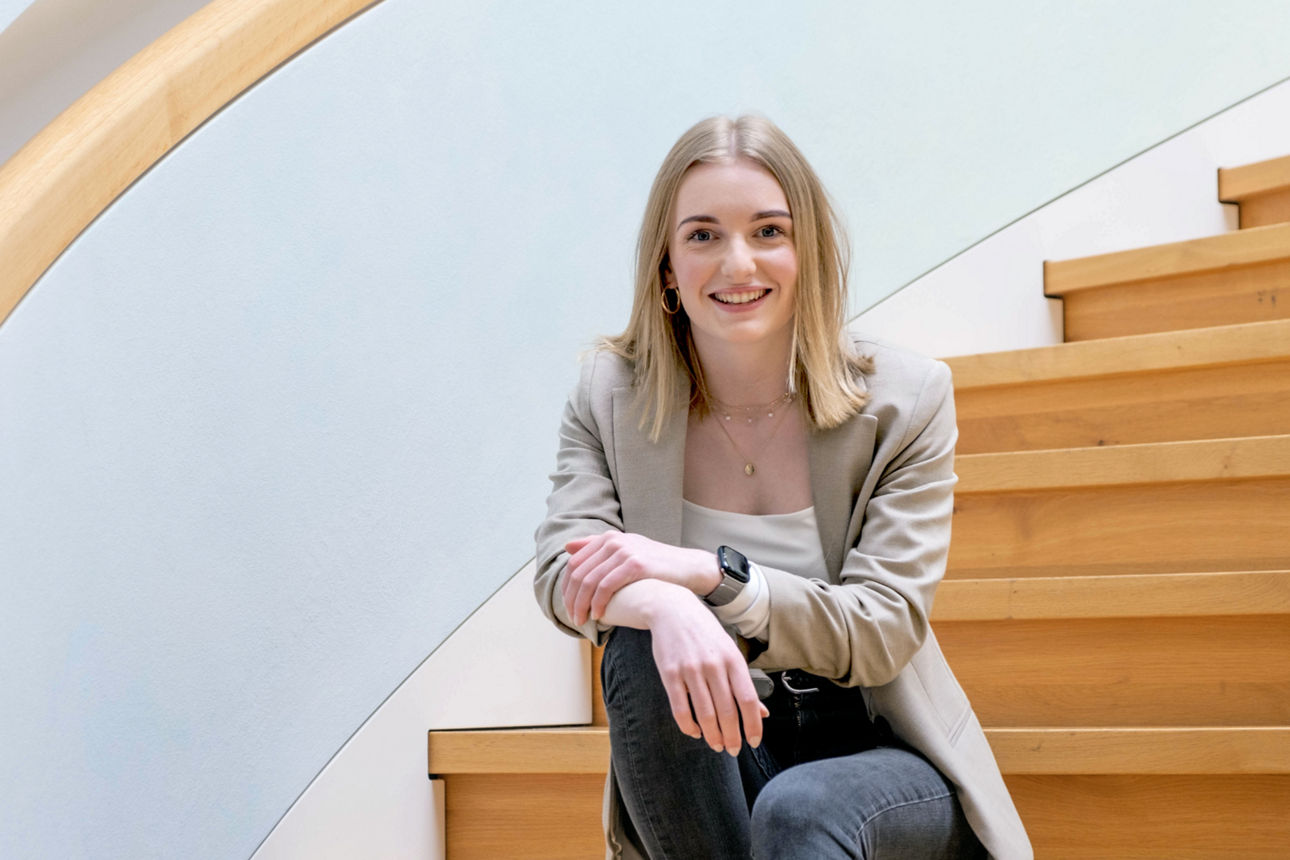 Junge Bankmitarbeiterin sitzt auf einer Treppe