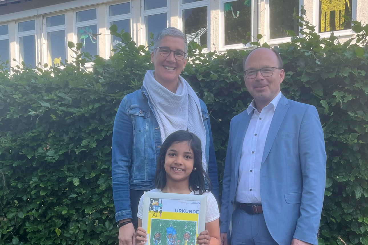 Eine Frau, ein Mann gemeinsam mit der Gewinnerin des Kunstwettbewerbs. 