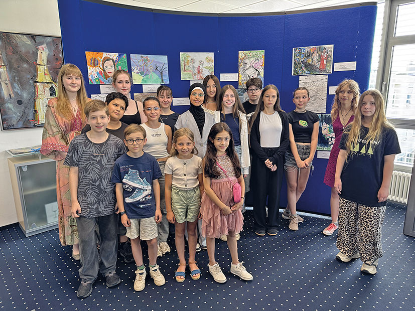 Gruppe Kinder stehen vor einer Wand mit Bildern 