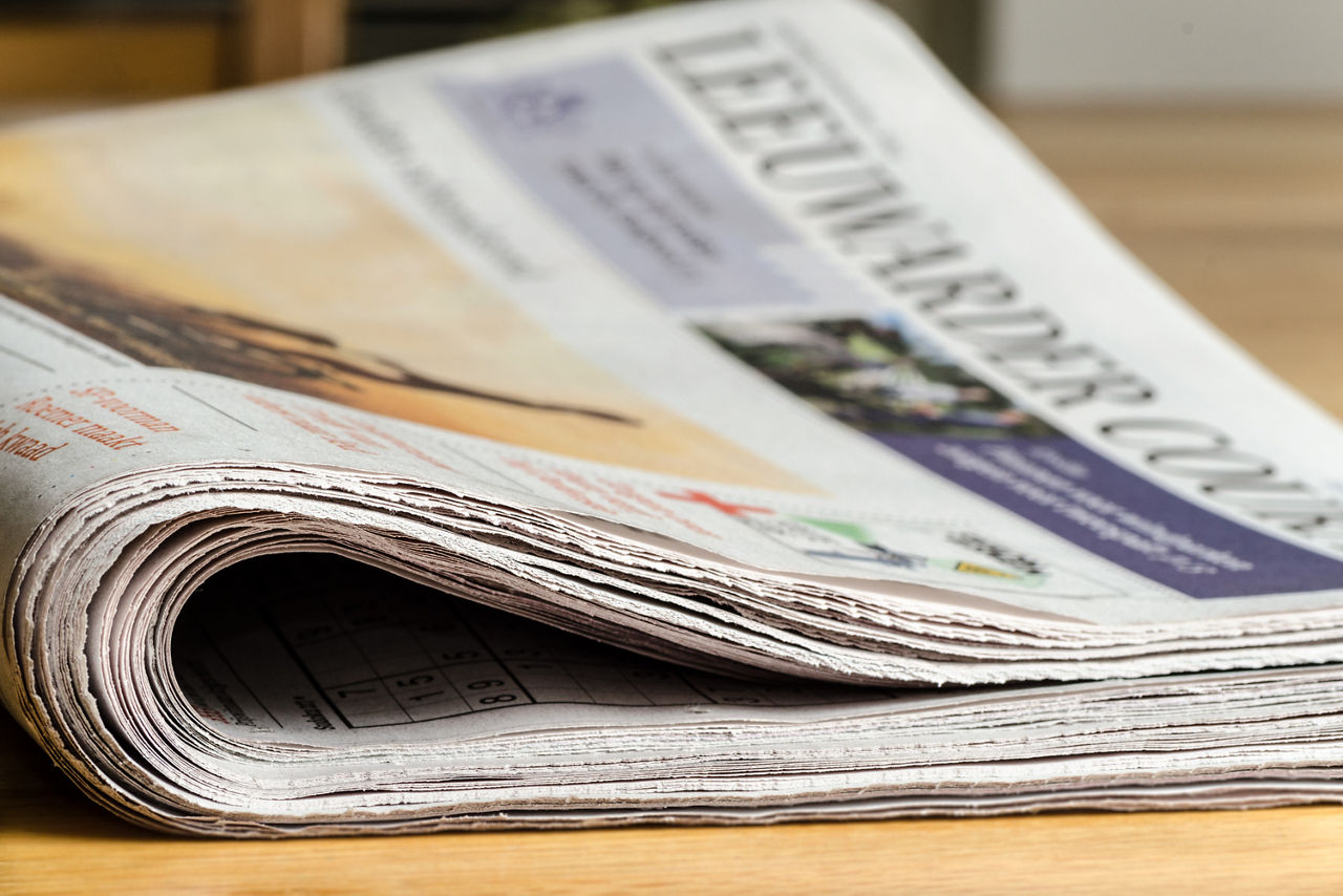 Eine Zeitung liegt geschlossen auf einer Holzoberfläche