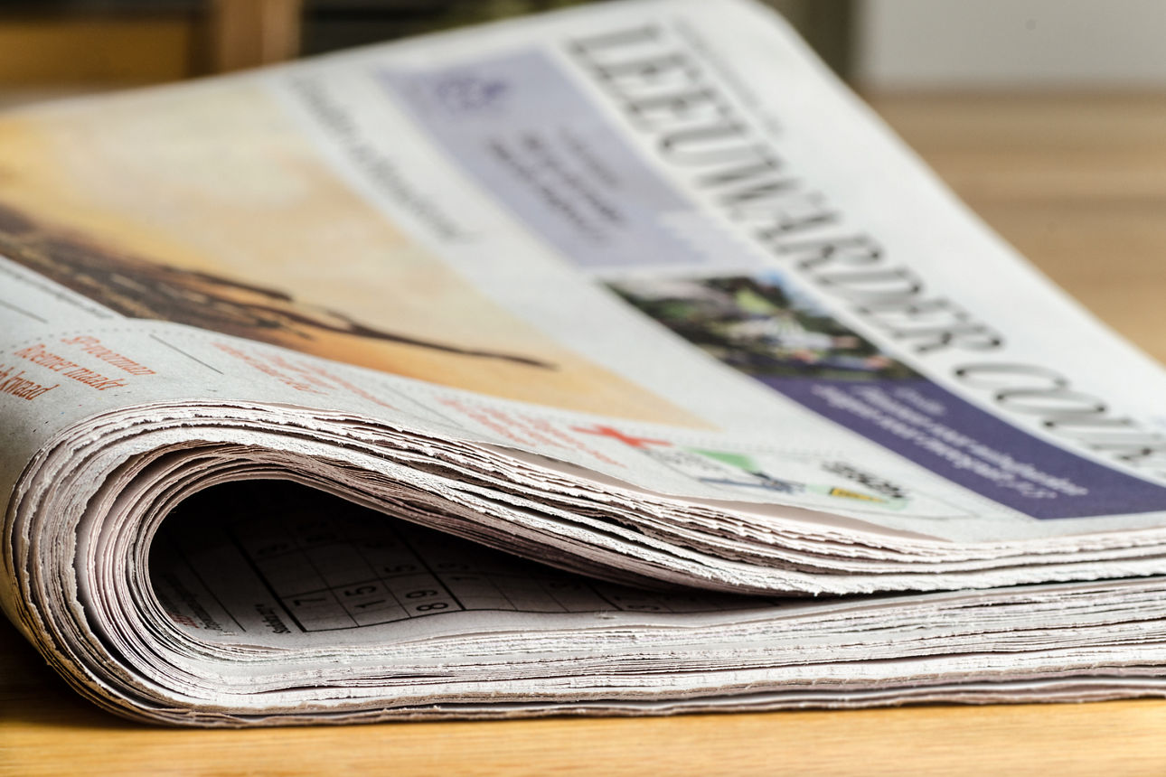 Eine Zeitung liegt geschlossen auf einer Holzoberfläche