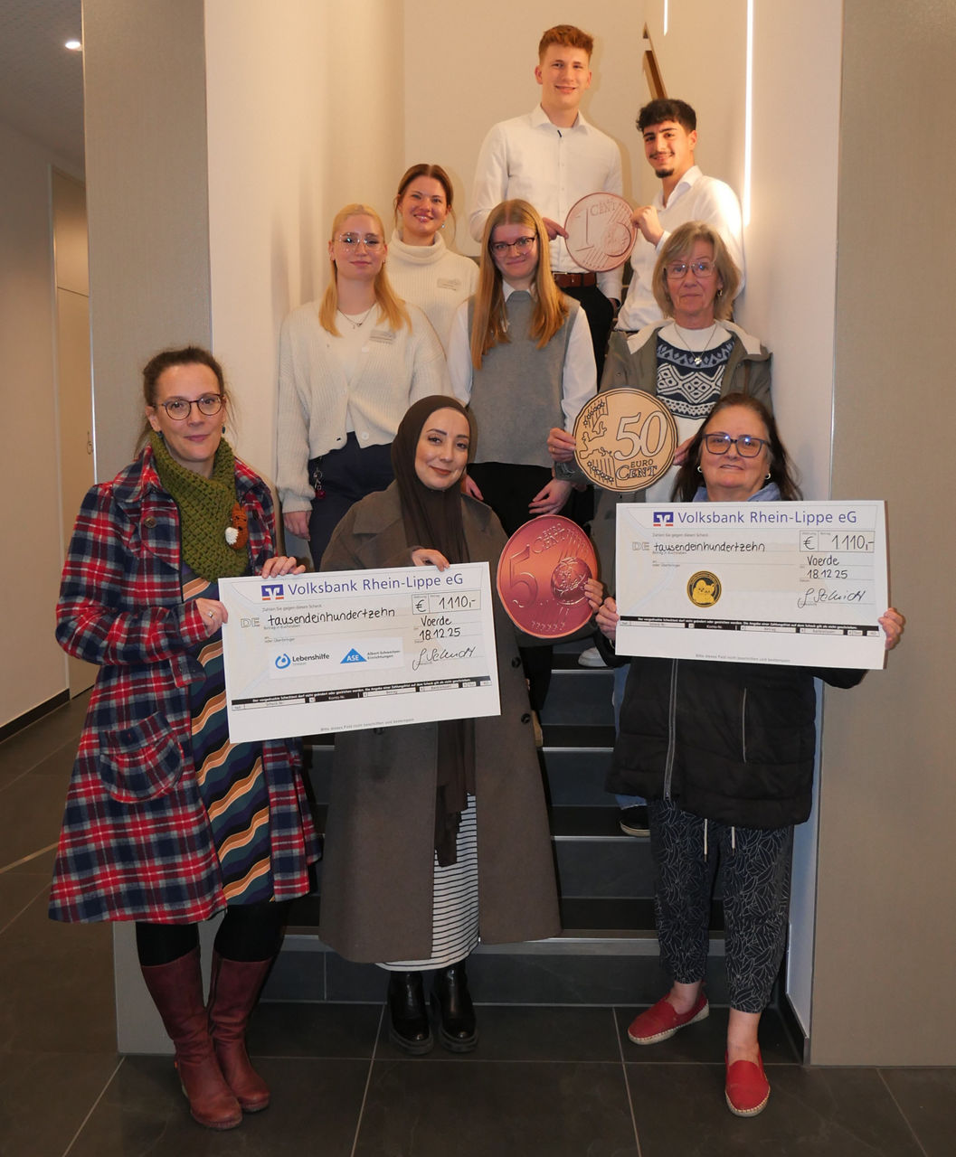 Menschen stehen in einem Gang und halten einen Spendenbeleg hoch