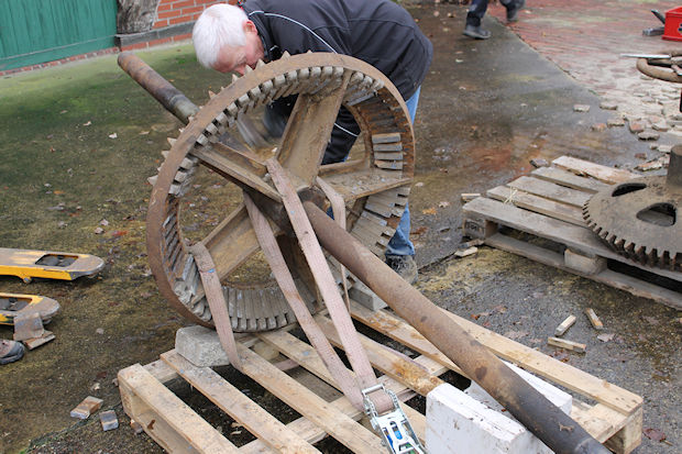 Ein großes Metallgetriebe wird demontiert. Es liegt auf der Seite und ruht auf einer Holzpalette.
