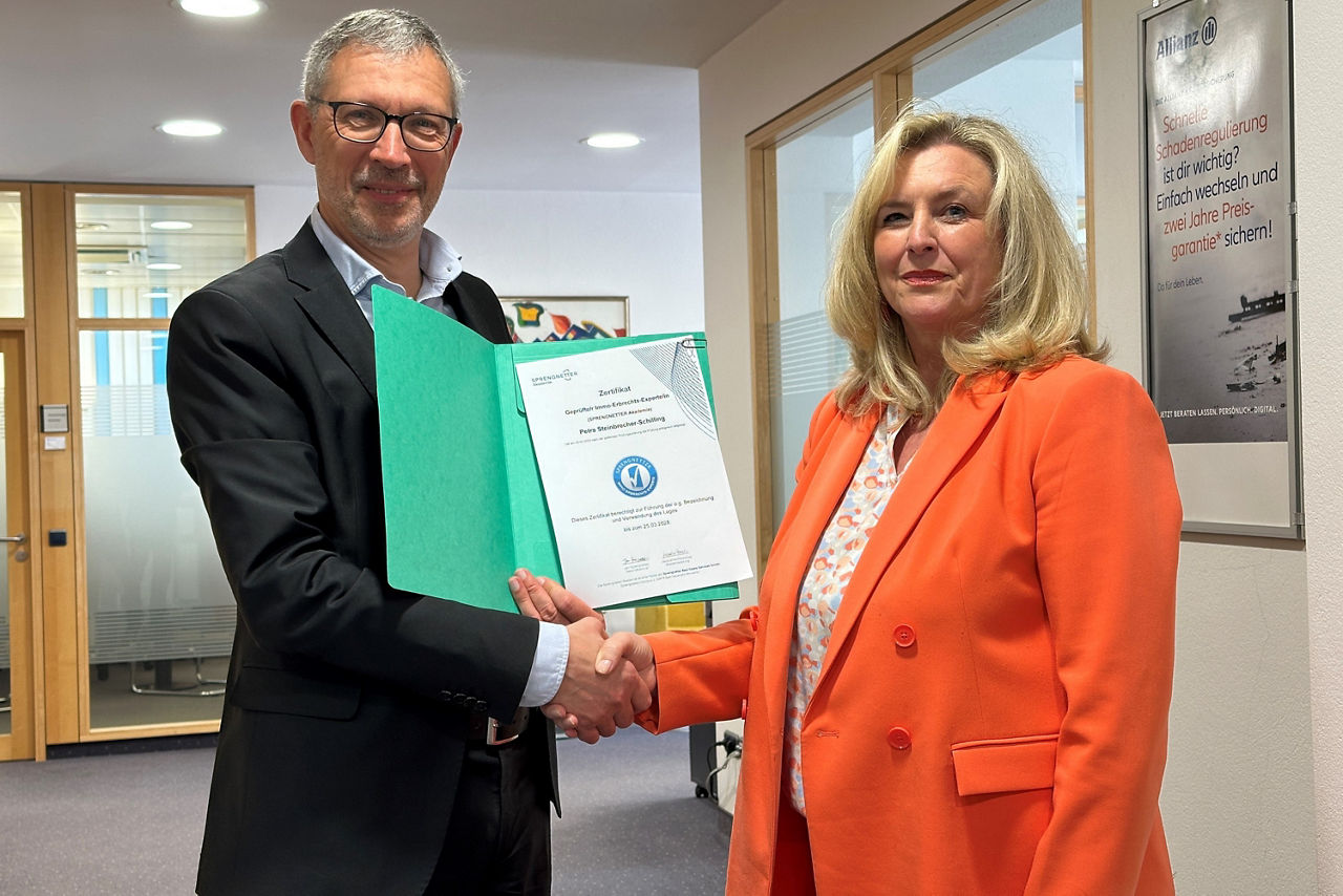 Ein Mann und eine Frau stehen nebeneinder und schütteln sich die Hand