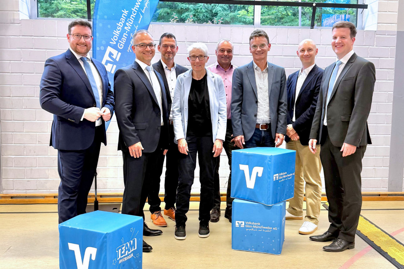 Eine Gruppe von Herren in Anzügen in einer Sporthalle.