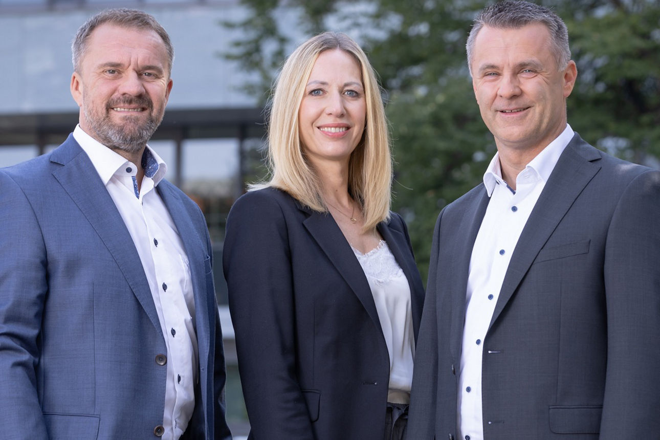 Die drei Vorstände der PSD Bank Nürnberg stehen nebeneinander vor der PSD Bank.