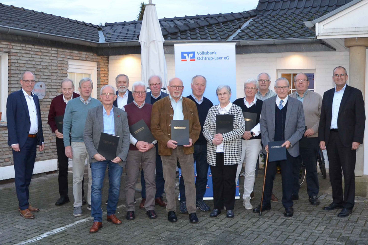 Gruppenfoto von geehrten Mitgliedern einer Volksbank-Veranstaltung vor dem Gebäudeeingang.“