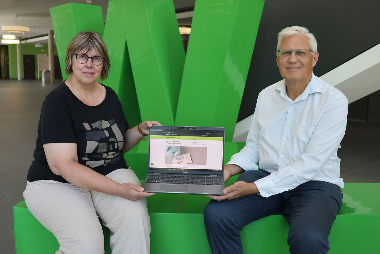 Links sitzt Kirsten Brenner, die Vertreterin der Studienberatung an der Westfälischen Hochschule Gelsenkirchen und rechts Herr Uhlenbruch, Vertreter der Volksbank Ruhr Mitte. Beide halten zwischen sich einen aufgeklappten Laptop und lächeln freundlich in die Kamera.