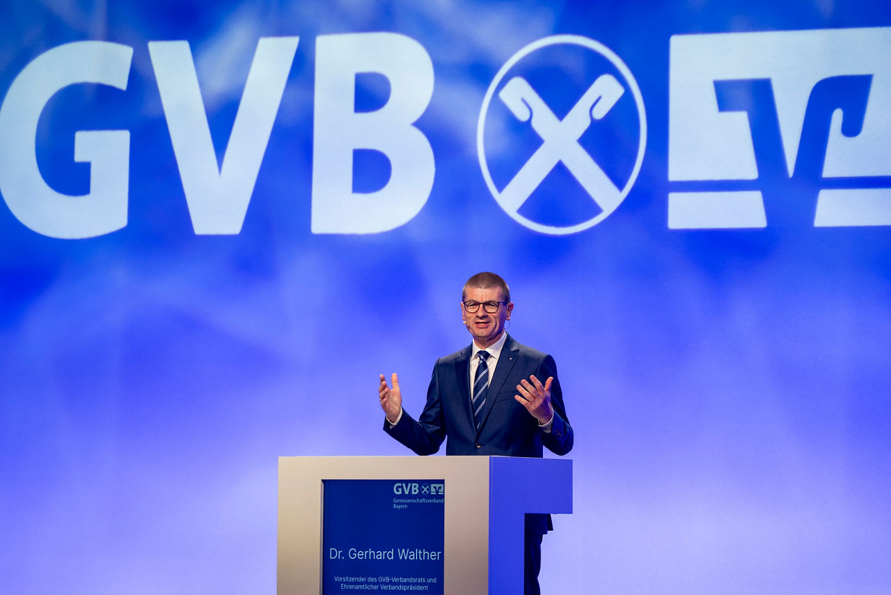Herr Dr. Gerhard Walther steht am Rednerpult auf Bühne mit großem GVB-Logo im Hintergrund