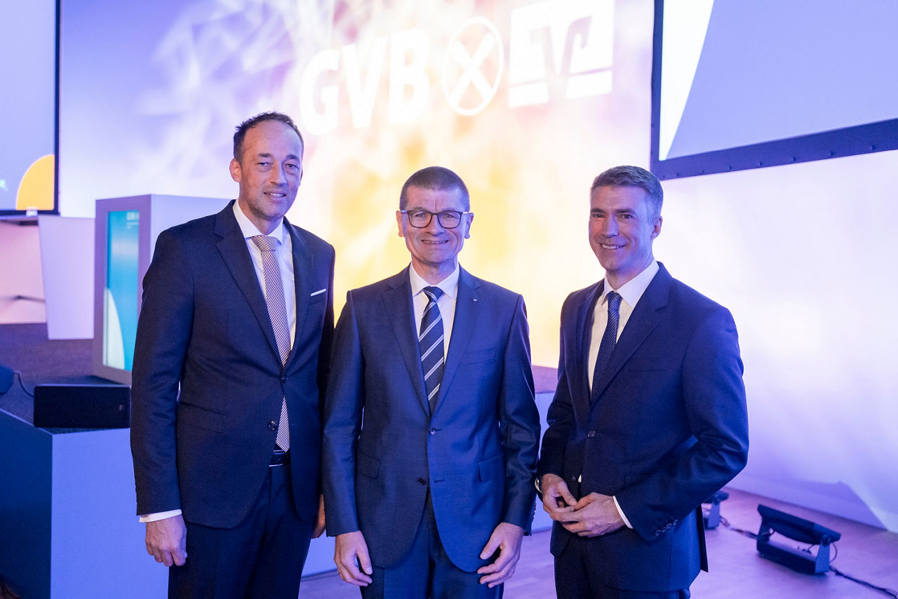Gruppenfoto dreier Männer vor Bühne des GVB 