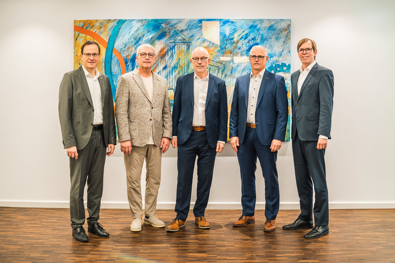 Fünf Männer in Anzügen stehen nebeneinander vor abstraktem Gemälde, offizielles Gruppenfoto