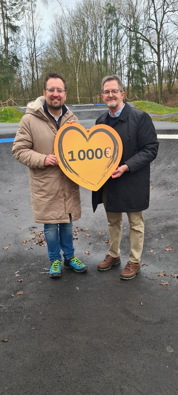 Auf dem Bild stehen Herr Florian Liening-Ewert und Herr Hans-Peter Suckfüll, die ein Schild mit dem Spendenbeitrag halten.