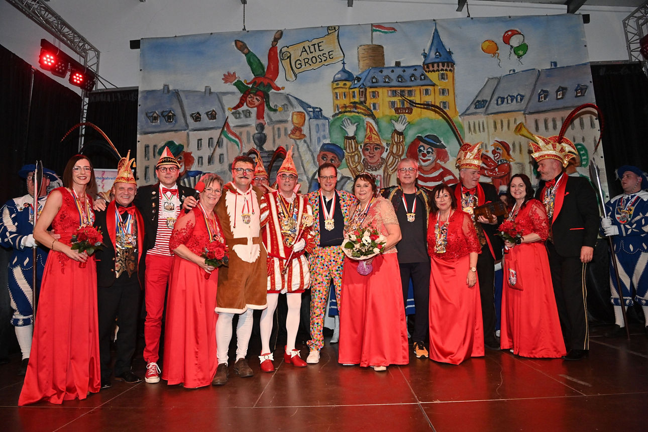 Gruppe in roten Kleidern und bunten Karnevalskostümen bei Karnevalsempfang auf Bühne