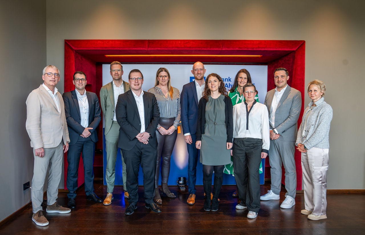 Mehrere Personen stehen in einem Raum zu einem Gruppenbild zusammen.