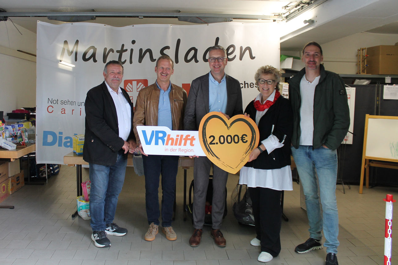 Die VR-Bank Main-Rhön übergibt eine Spende von 2.000 Euro an den Martinsladen in Bad Neustadt. Auf dem Foto stehen fünf Personen nebeneinander und halten ein großes Schild in Herzform mit der Spendensumme.