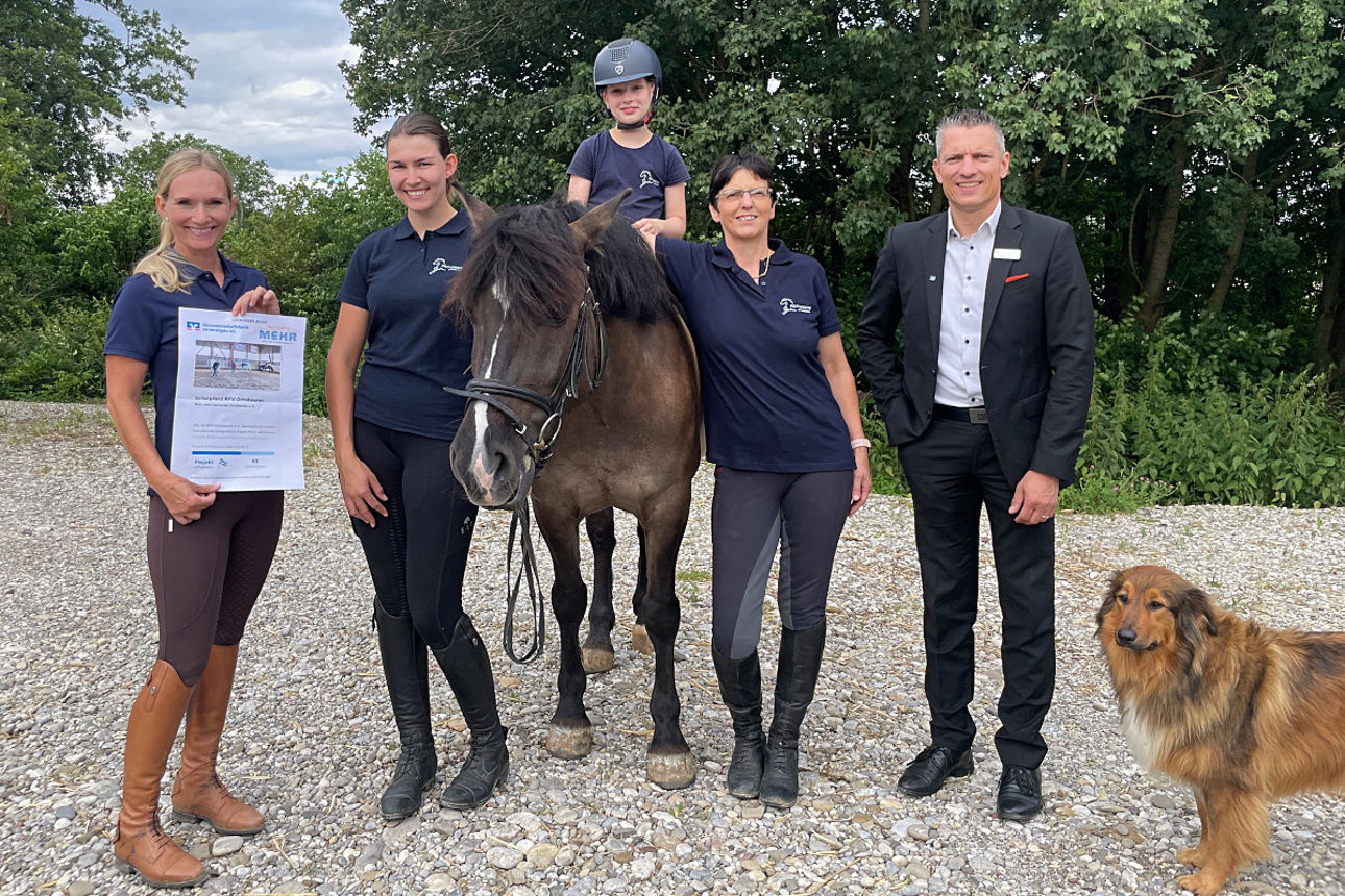 Mitglieder des Vereins stehen mit einem Pferd nebeneinander. Daneben steht ein Mitarbeiter der Bank