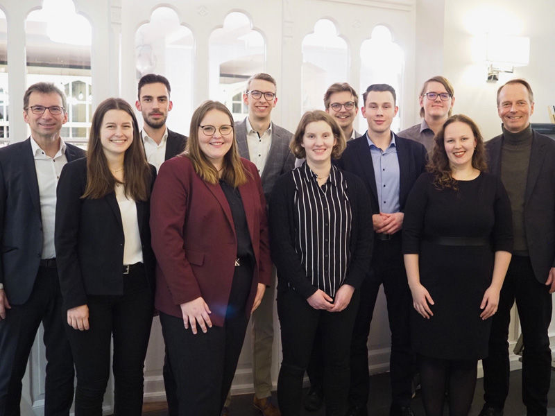 Sechs Auszubildende der Volksbank eG stehen in einer Gruppe mit Mitarbeitenden und dem Vorstandsvorsitzenden der Bank. 
