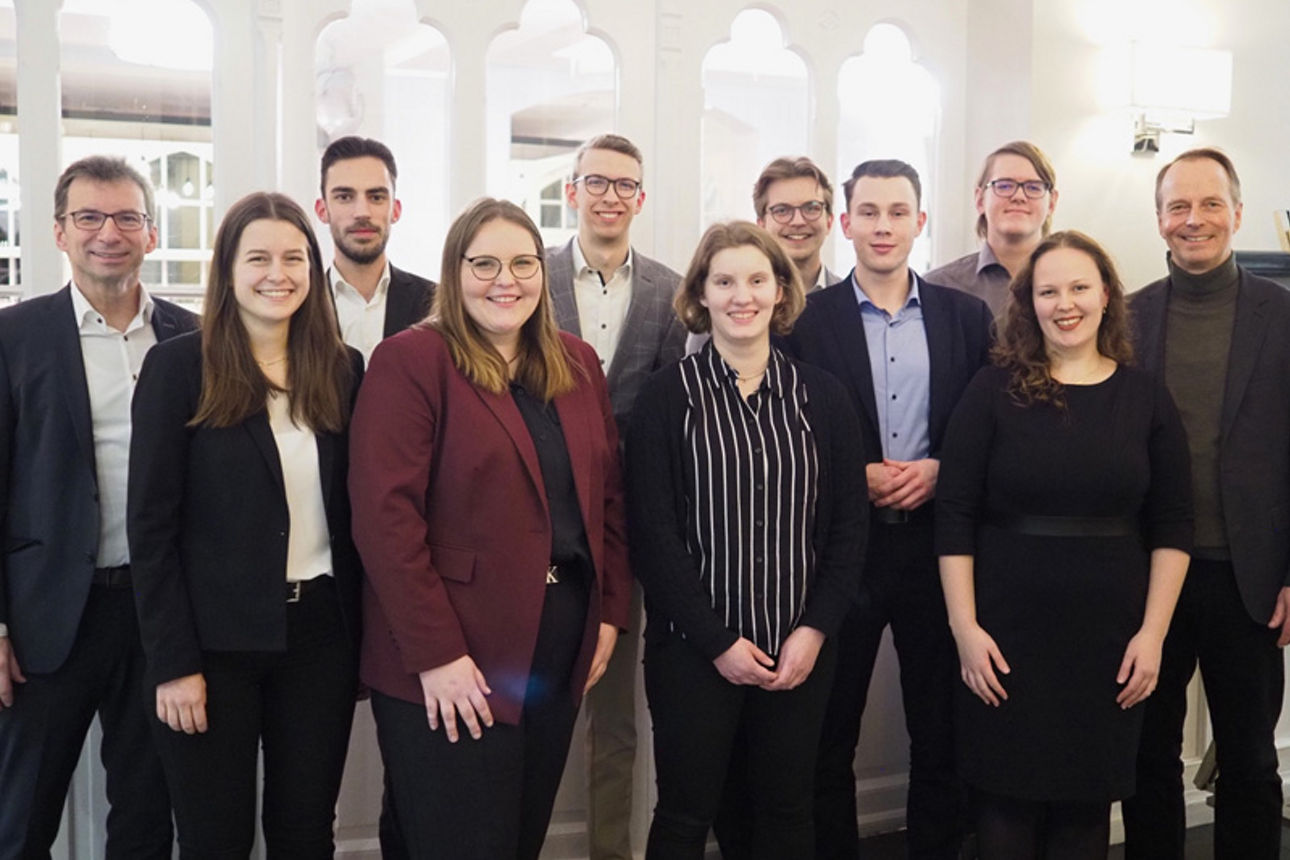 Sechs Auszubildende der Volksbank eG stehen in einer Gruppe mit Mitarbeitenden und dem Vorstandsvorsitzenden der Bank. 