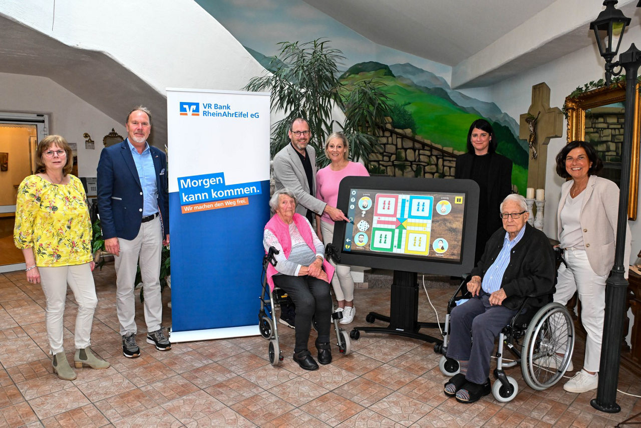 Das Bild zeigt mehrere Personen, die sich in einem Seniorenzentrum zu einem Gruppenbild aufgestellt haben.