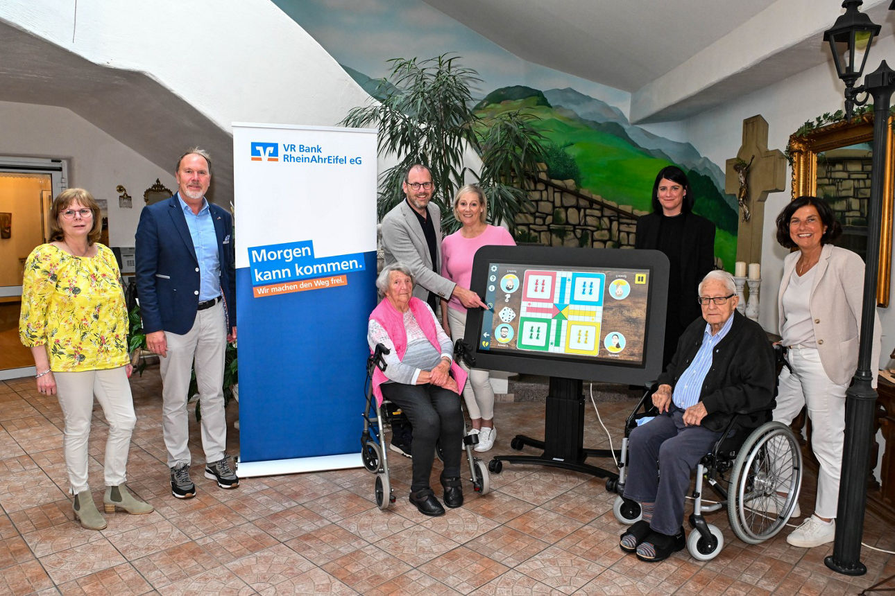 Das Bild zeigt mehrere Personen, die sich in einem Seniorenzentrum zu einem Gruppenbild aufgestellt haben.
