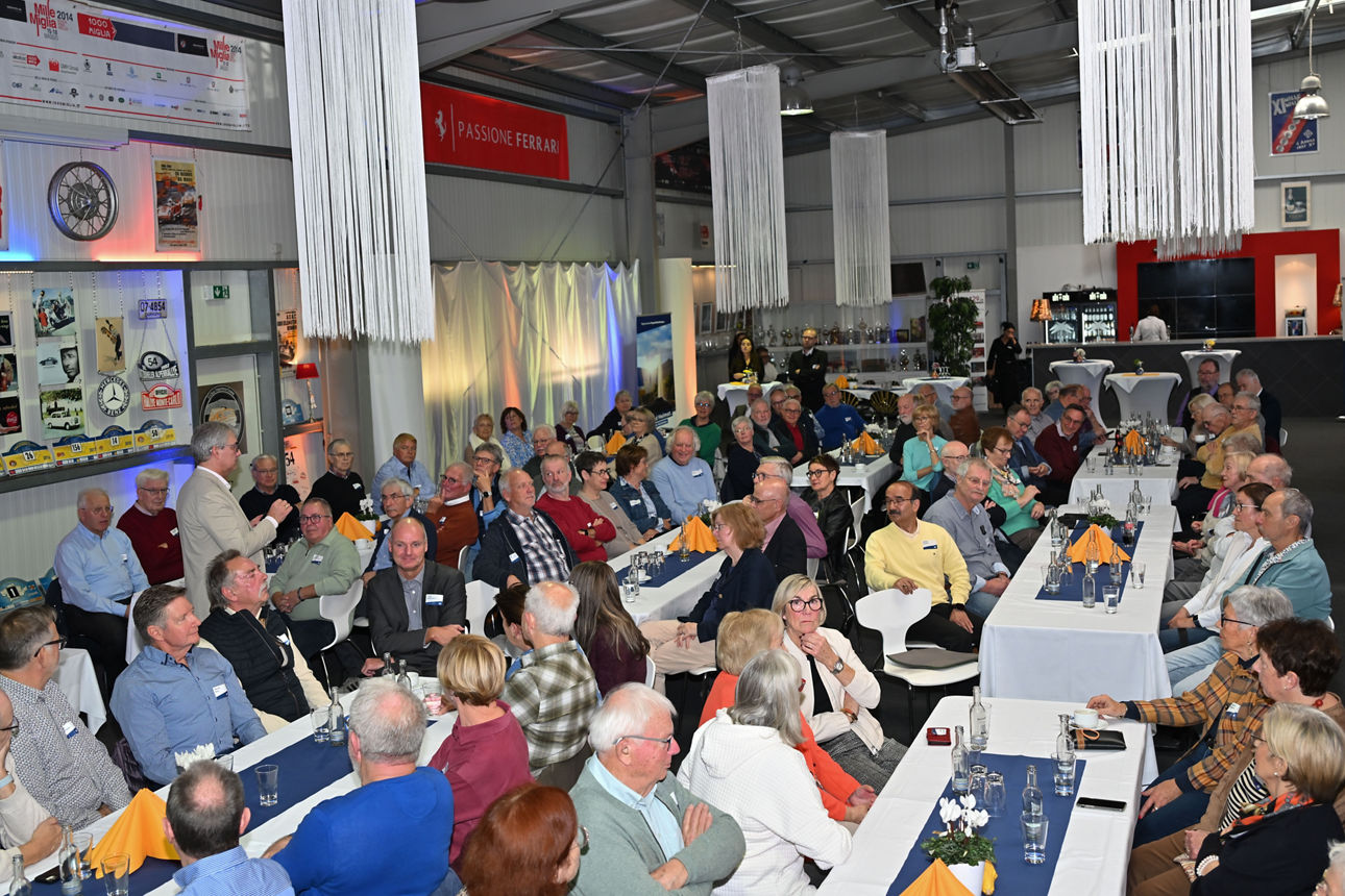  Ehemaligentreffen der VR Bank RheinAhrEifel eG mit älteren Gästen an festlich gedeckten Tischen in einer automobilen Eventlo