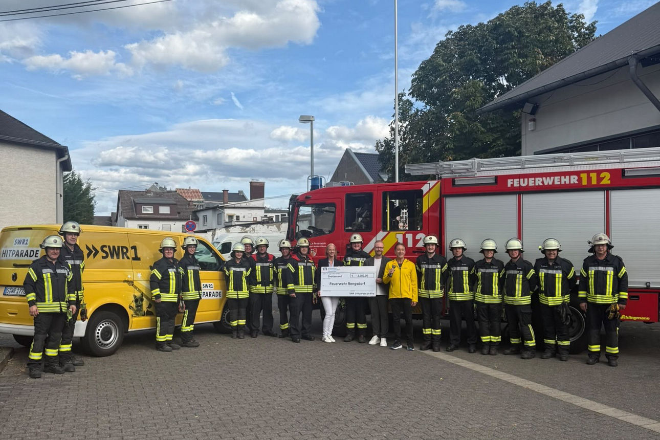 Mitglieder der Feuerwehr Rengsdorf präsentieren gemeinsam mit einem Vertreter des Radiosenders SWR1 vor der Feuerwehrwache ei
