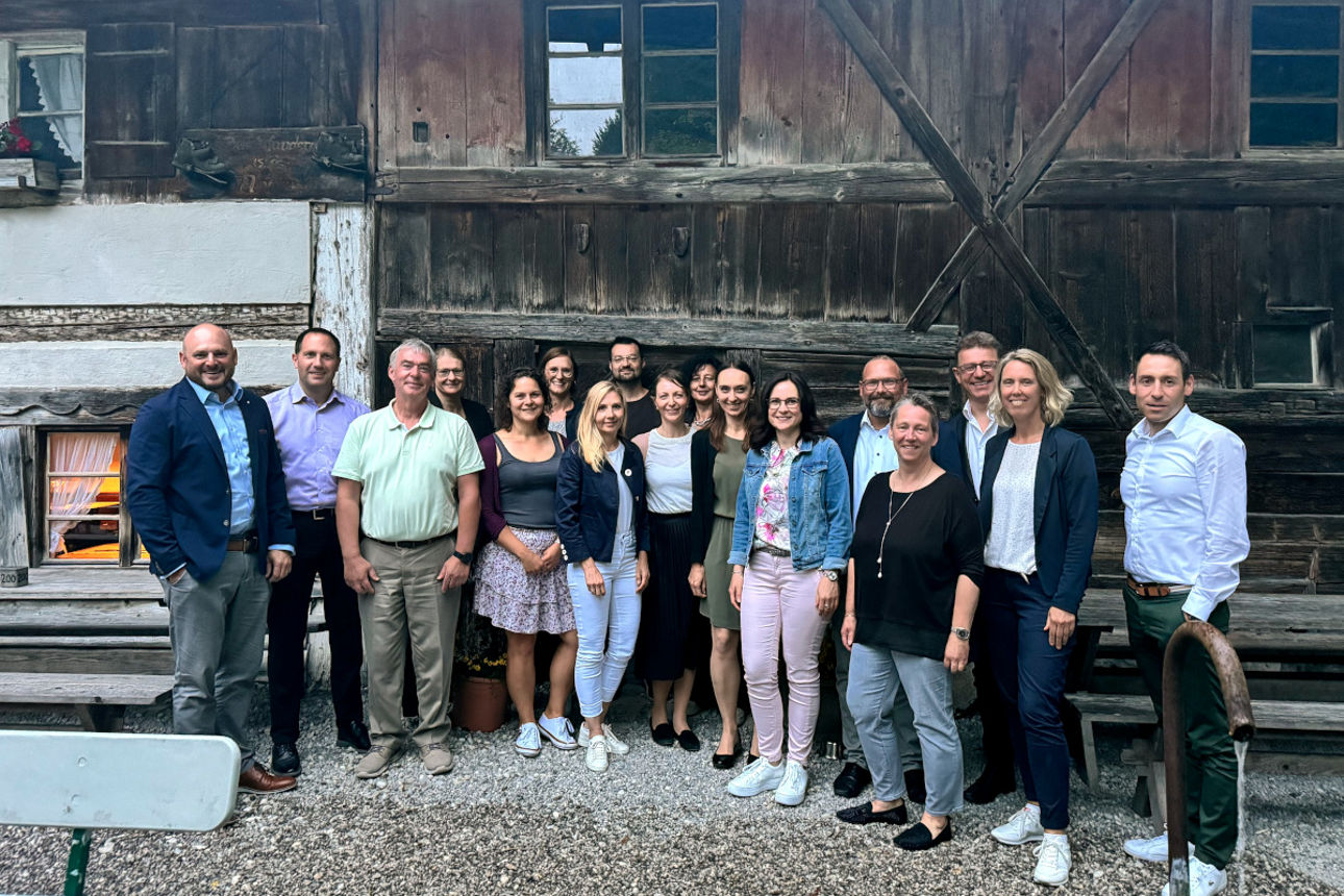 Mitarbeiter stehen nebeneinander vor einem alten Bauernhaus
