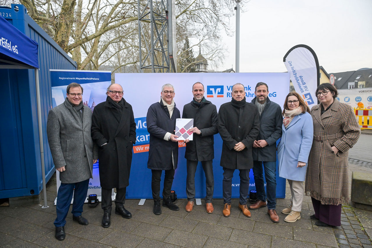 Mehrere Personen stehen im Freien einem Gruppenbild zusammen. 