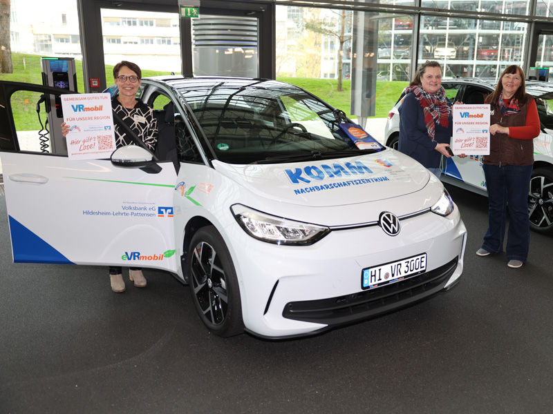 Eine Person steht links und zwei Personen stehen rechts neben dem eVRmobil
