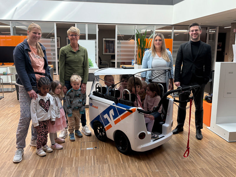 Vier Erwachsene stehen mit acht Kindern vor einem Kinderbus in der Geschäftsstelle Hildesheim