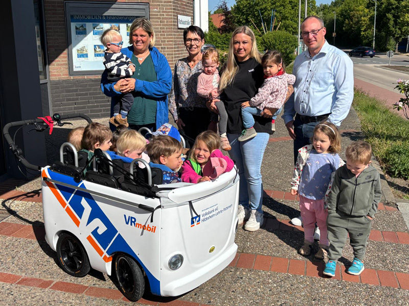 Vier Erwachsene stehen mit Kindern vor einem Kinderbus vor der Geschäftsstelle Nordstemmen