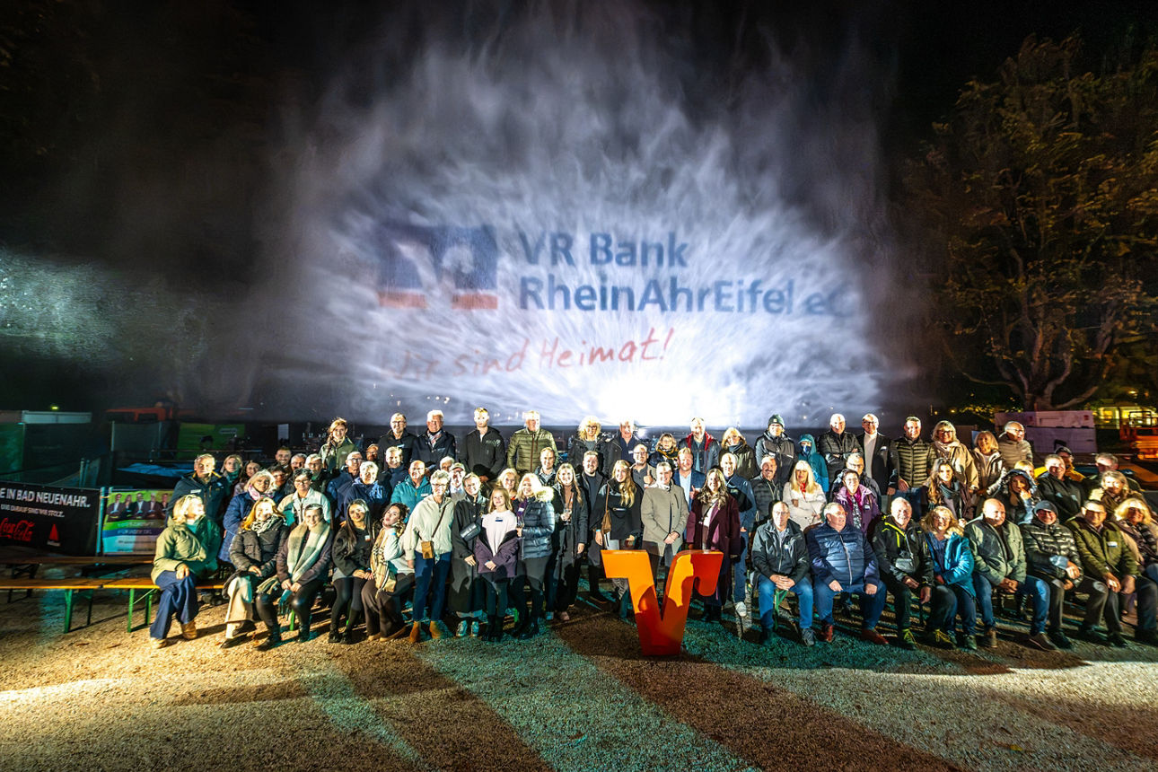 Großes Gruppenfoto mit zahlreichen Menschen in Winterkleidung bei einer abendlichen Open-Air-Veranstaltung