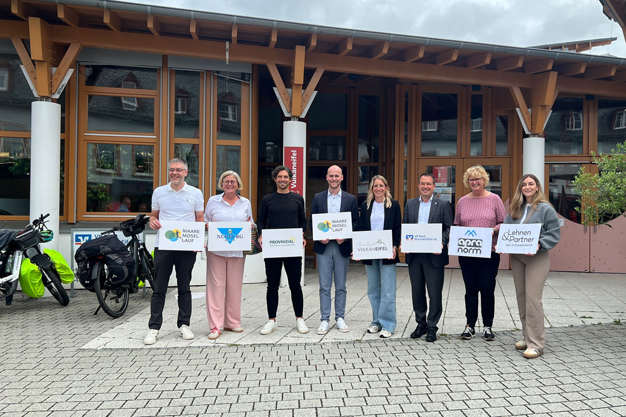 Acht Personen vor „Vulkaneifel“-Gebäude mit Schildern: Maare Mosel Lauf,  VR Bank