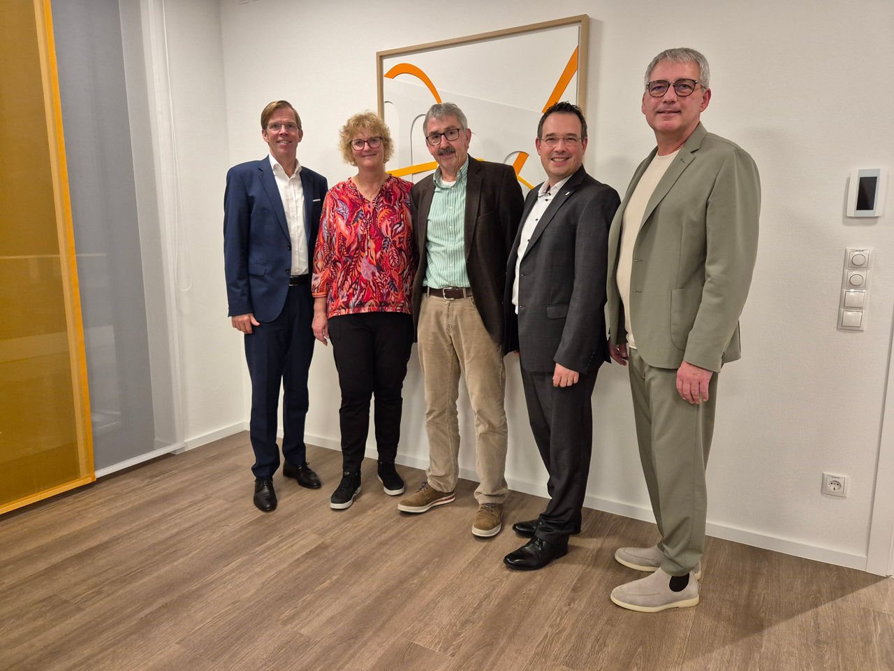 Fünf Personen stehen in einem Raum zu einem Gruppenbild zusammen.